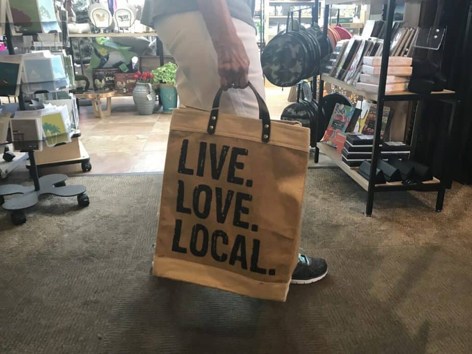 A woman is shopping and carries a bag that says live. Love. Local.