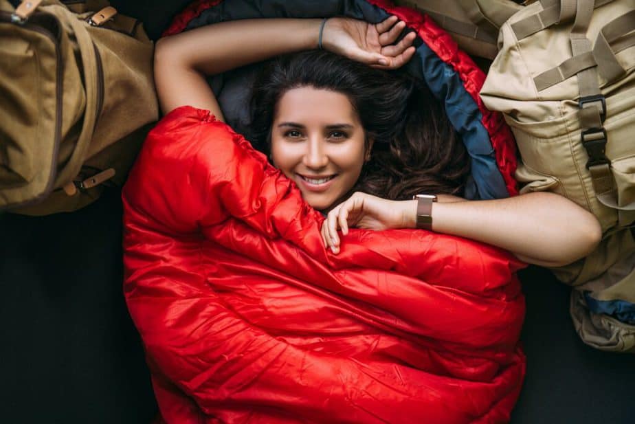 A young woman in a comfortable sleeping bag in a tent, top view. A tourist in a sleeping bag