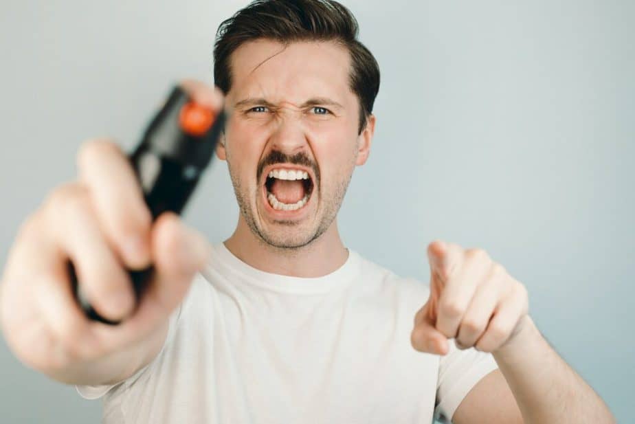 Man using self-defense device, close-up, selective focus. Young man holding pepper spray, screams