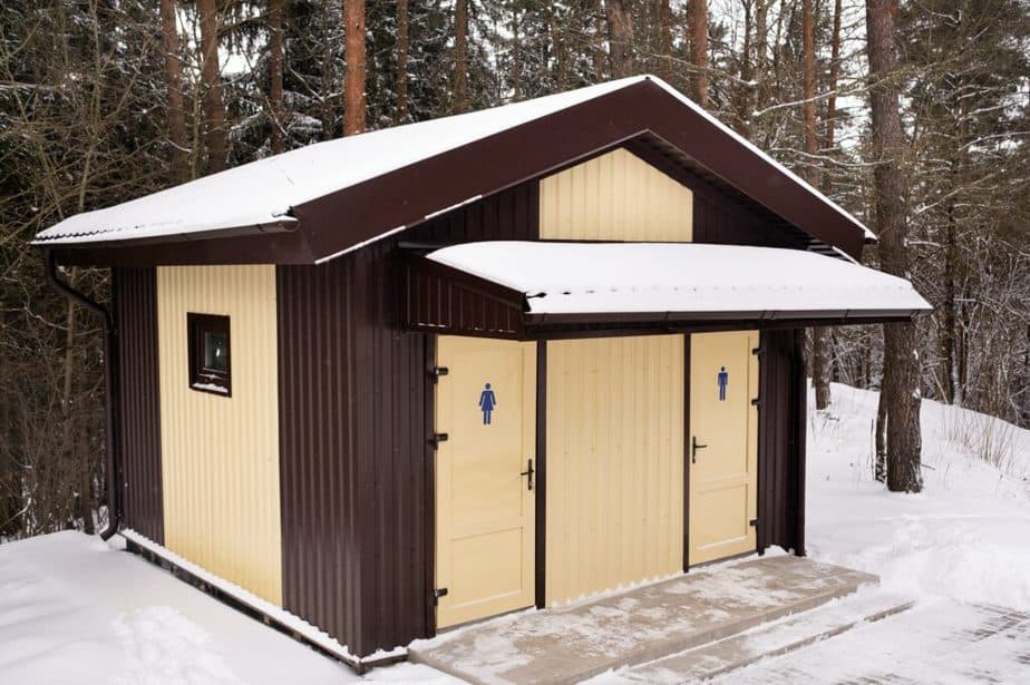 Men's and women's toilets standing in a snowy forest