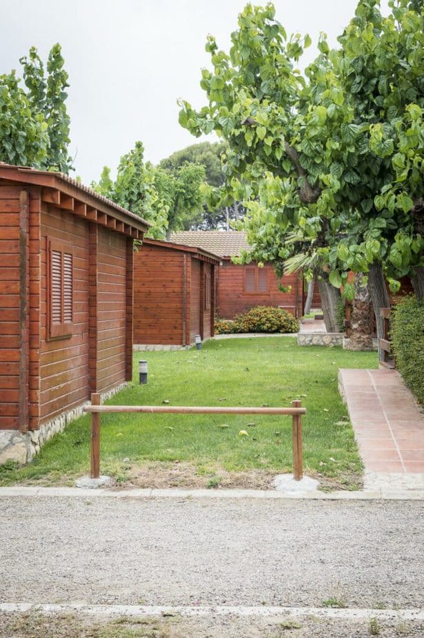 Wooden bungalows in a campsite with a lawn area.